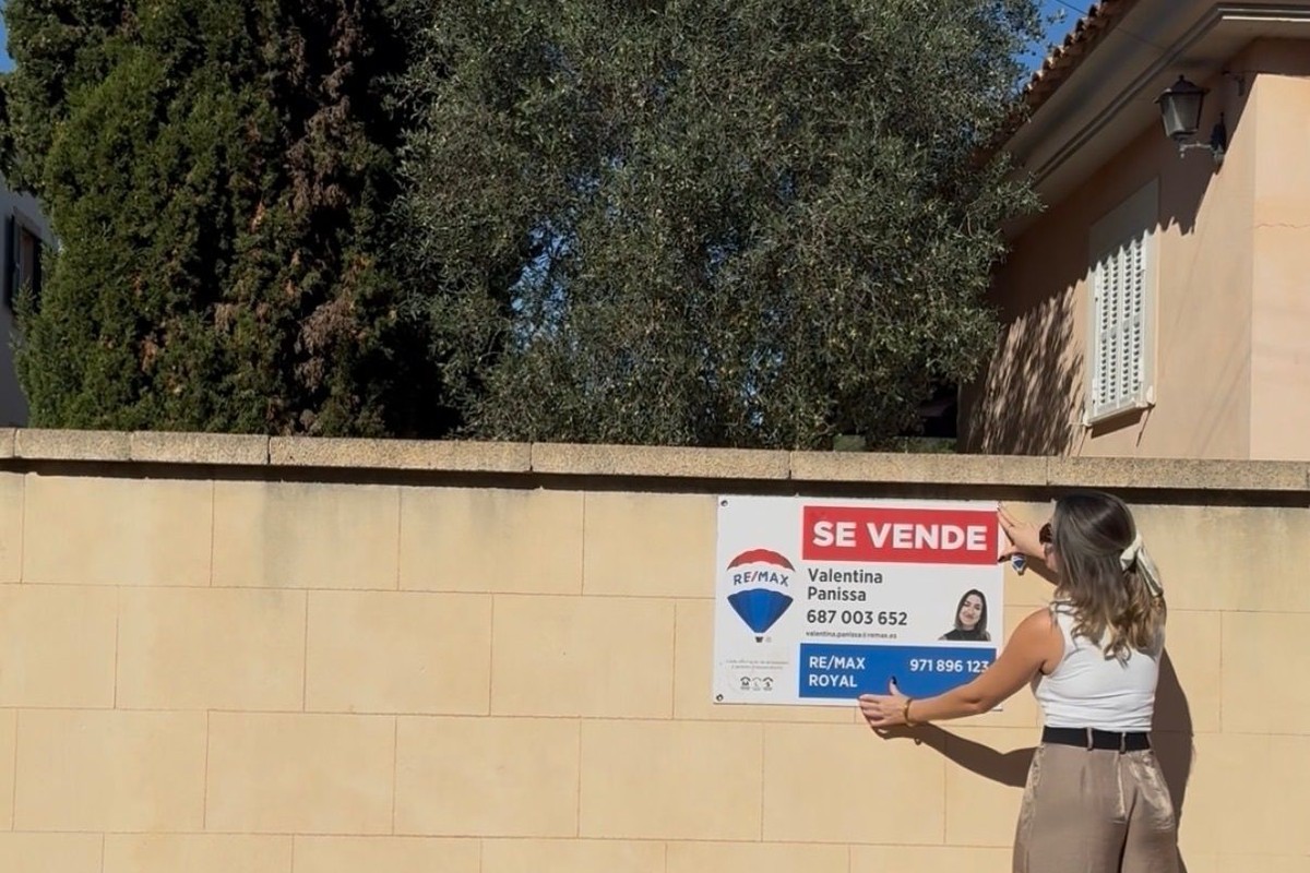 Valentina Panissa colocando el cartel de se vende de RE/MAX en una vivienda de Mallorca